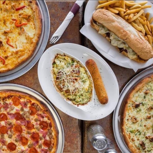 Valentino's NY Pizza spread with three pizzas, baked pasta, a sub sandwich, and fries.